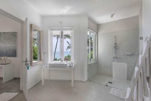 a white bathroom with a table and two windows at The Sandals By Edwards Collection in Hikkaduwa