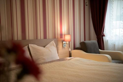 a hotel room with a bed and a chair and a lamp at Apartamente Felix in Baile Felix
