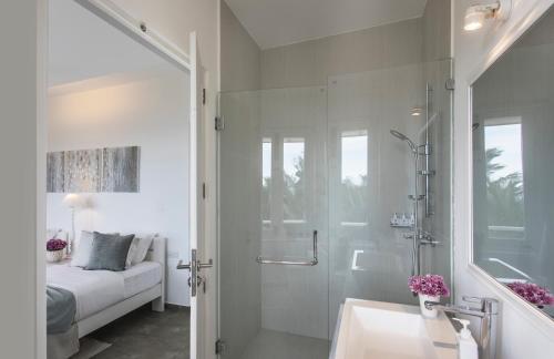 a bathroom with a shower and a sink and a bed at The Sandals By Edwards Collection in Hikkaduwa