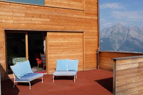 two chairs sitting on a patio with mountains in the background at Iglusaq Lodge in Veysonnaz