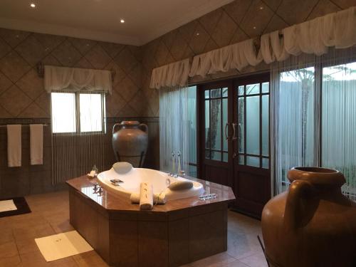 een grote badkamer met een bad en een groot raam bij Witwater Guest House & Spa in Kempton Park