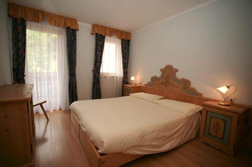 a bedroom with a large bed and two windows at Casa Maurivan in Canazei