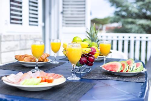 a table with plates of fruit and glasses of orange juice at Apartments The heart of Croatia in Pirovac