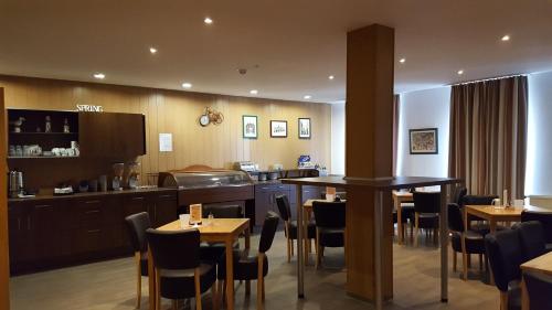 a restaurant with tables and chairs and a kitchen at Hotel Am Kleinbahnhof in Emden