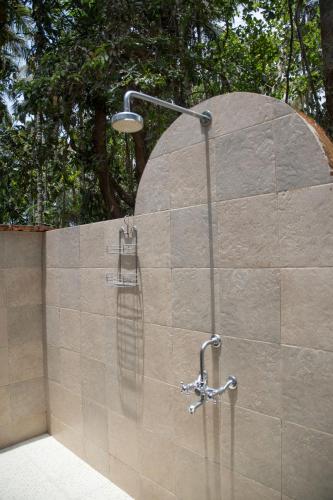 a shower in a stone wall with a shower head at Dudhsagar Plantation in Cormonem