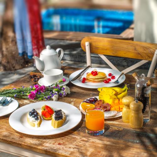 a table with plates of breakfast foods and orange juice at Amritara Aura Resort & Spa in Mandrem
