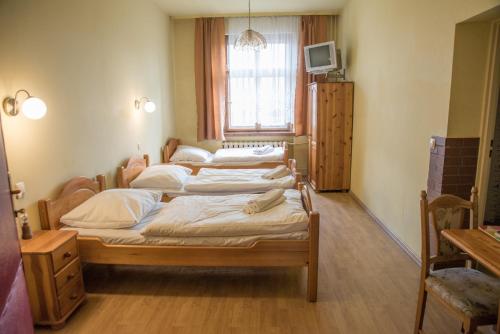 a group of four beds in a room with a window at Hotel Azyl in Gorzów Wielkopolski