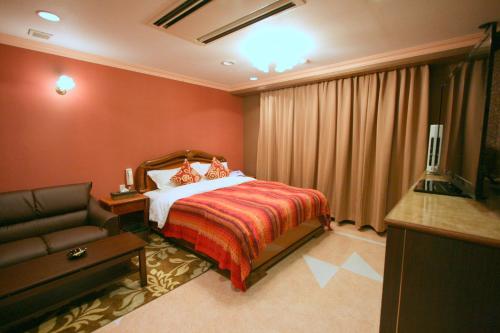 a hotel room with a bed and a couch at Aura Ono (Adult Only) in Ono