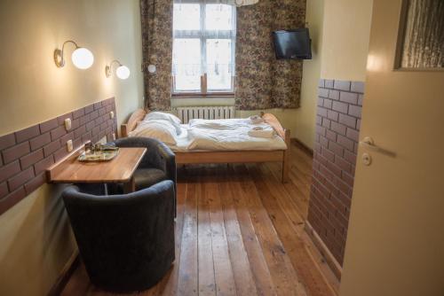 a small room with a bed and a table and chairs at Hotel Azyl in Gorzów Wielkopolski