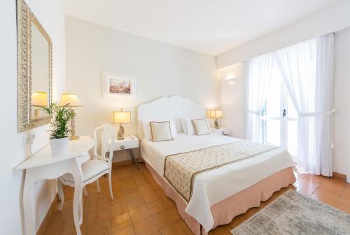 a white bedroom with a bed and a table and chairs at Villa Romana Hotel & Spa in Minori