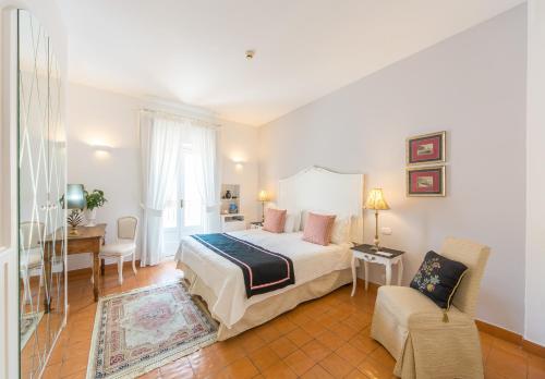 a bedroom with a bed and a desk and a chair at Villa Romana Hotel & Spa in Minori
