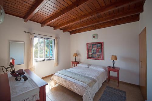 1 dormitorio con 1 cama, 2 mesas y una ventana en Casa do Chafariz (Casas do Capelo), en Varadouro