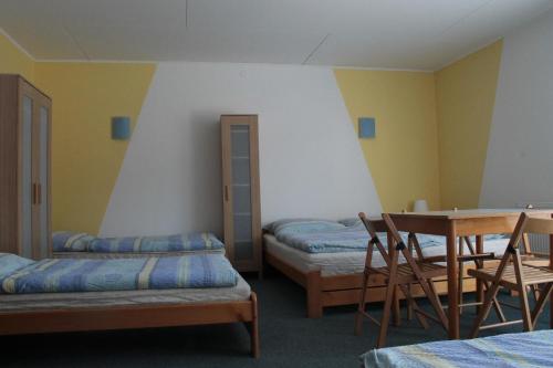 リポヴァー・ラーズニェにあるpenzion Pomněnkaのベッド2台、テーブル、椅子が備わる客室です。