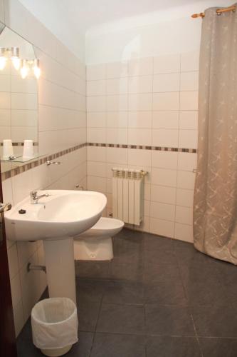 a white bathroom with a sink and a toilet at Residencial Parque in Celorico da Beira