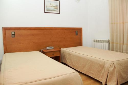 a room with two beds and a clock on the wall at Residencial Parque in Celorico da Beira