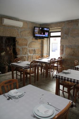 a dining room with tables and chairs and a tv at Residencial Parque in Celorico da Beira