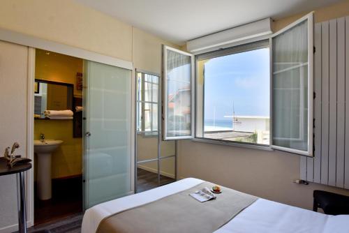 a hotel room with a bed and a view of the ocean at Logis Hotel de France in Mimizan-Plage