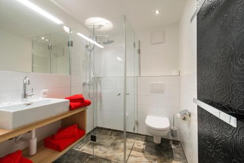 a bathroom with a sink and a toilet and a shower at Boutiquethotel Grandau in Sankt Gallenkirch