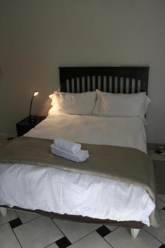 a bed with white sheets and pillows with two towels on it at De Vagebond Hotel-Pension in Windhoek