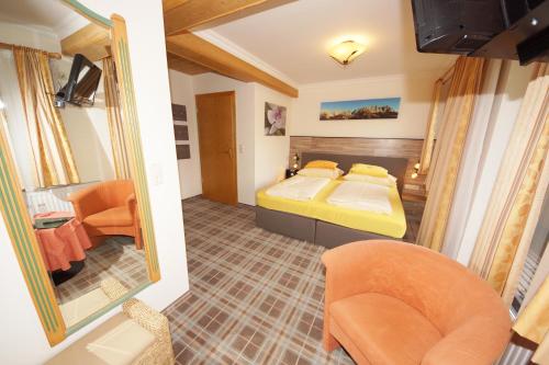 a bedroom with a bed and two chairs in it at Pension Alexandra in Going am Wilden Kaiser