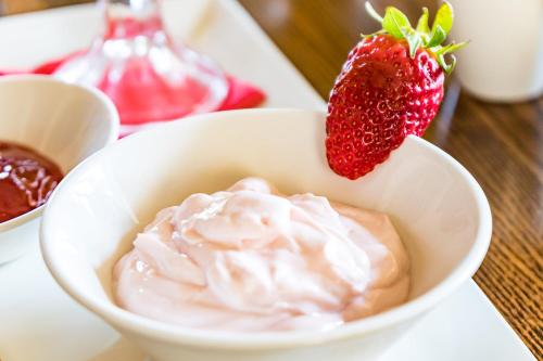 a bowl of whipped cream and a strawberry on a table at Il-Logga Boutique Hotel in Xagħra