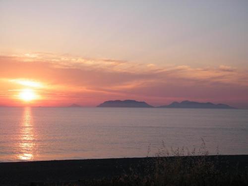 a sunset over the water with mountains in the distance at B&B Varadero in Milazzo