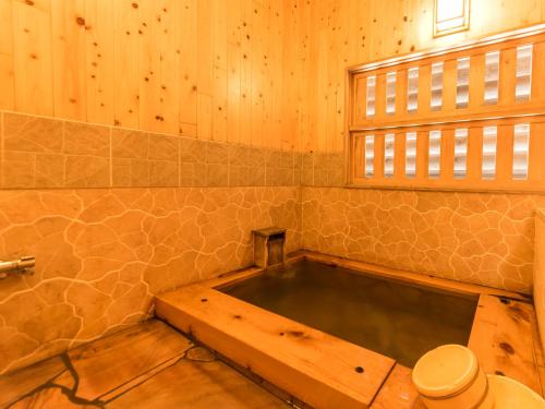 a bath tub in a bathroom with wooden walls at Takaosou in Yufuin