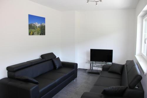 a living room with a black couch and a flat screen tv at Bergblick-Planai - 5 Schlafzimmer plus eigene Sauna in Schladming