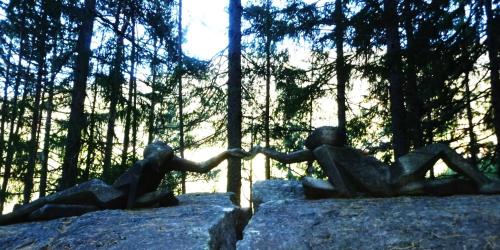 two statues of people sitting on rocks in a forest at Lahnerhof in Campo Tures