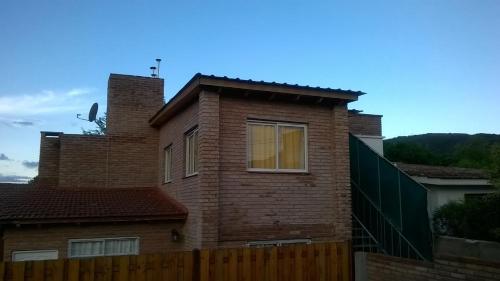 una casa de ladrillo con una valla delante en Departamento Con Vistas a La Montaña, en Villa Carlos Paz