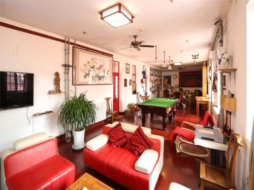 een woonkamer met een rode bank en een pooltafel bij Wheat Youth Hostel Qingdao in Qingdao