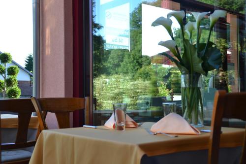 a table with a vase of flowers on it at Le Rhien Hôtel-Restaurant in Ronchamp
