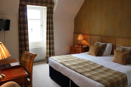 a hotel room with a bed and a desk and a window at Old Manor Hotel in Lundin Links