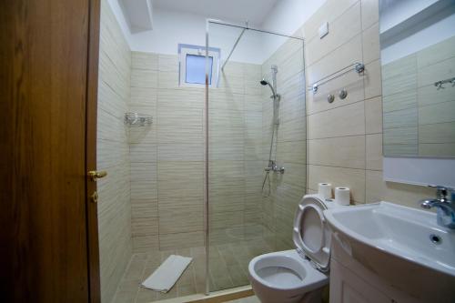 a bathroom with a shower and a toilet and a sink at Kollari Apartments in Ulcinj
