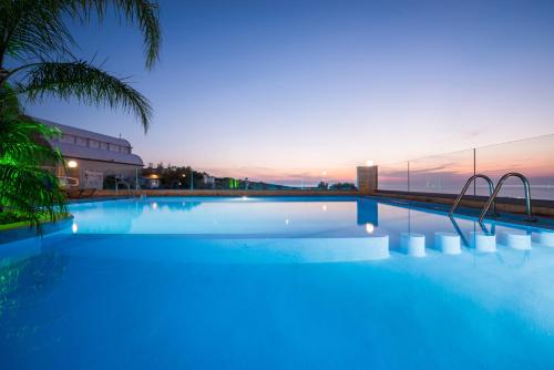 een groot zwembad met een zonsondergang op de achtergrond bij Esplanade Apartments in Kalathas