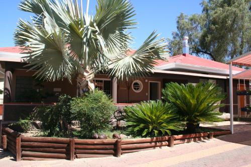 a house with a palm tree in front of it at De Vagebond Hotel-Pension in Windhoek