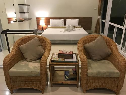 two chairs and a table in a room with a bed at Baancivilize Resort in Khanom