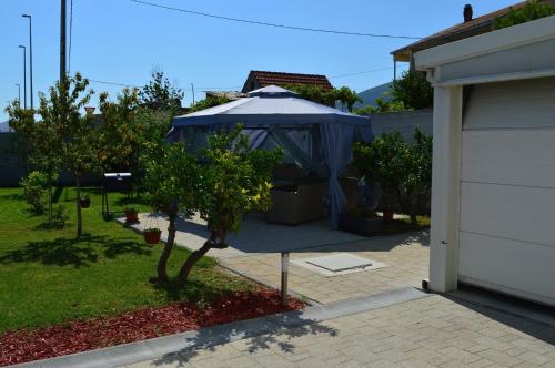 einen Hof mit einem blauen Regenschirm neben einer Garage in der Unterkunft Apartments Kristal in Kaštela