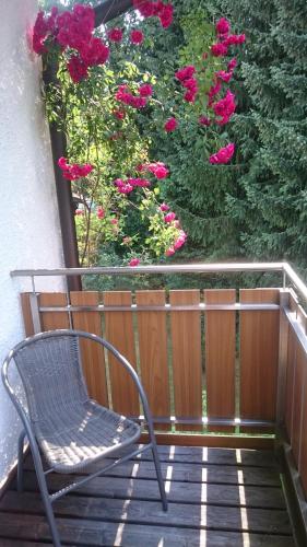 a chair sitting on a porch with pink flowers at Hotel am Wald in Ottobrunn