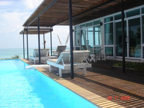 a house with a swimming pool next to the ocean at Baancivilize Resort in Khanom