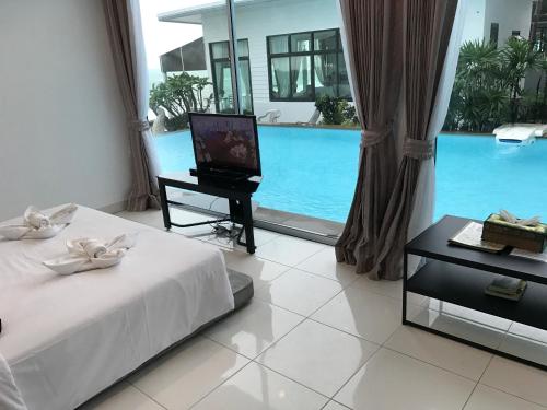 a bedroom with a bed and a television and a pool at Baancivilize Resort in Khanom