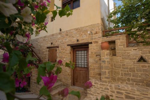 a stone building with a wooden door and flowers at Kritikies in Pitsidia