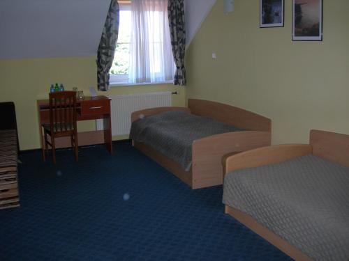 a room with two beds and a table and a desk at Zajazd Podjadek in Osjaków