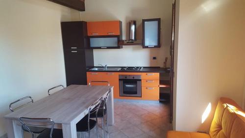una cucina con tavolo in legno e una cucina con armadietti arancioni di Corallo casa vacanza a Villaputzu