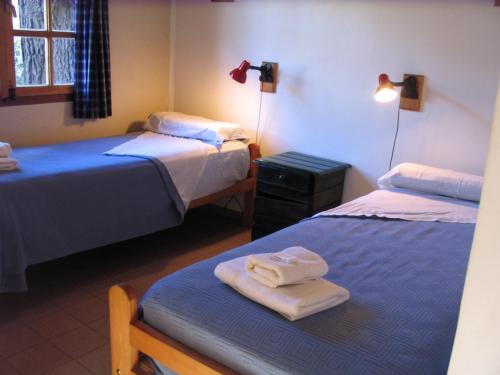 Habitación con 2 camas y una mesa con toallas. en Puma Hostel en San Martín de los Andes