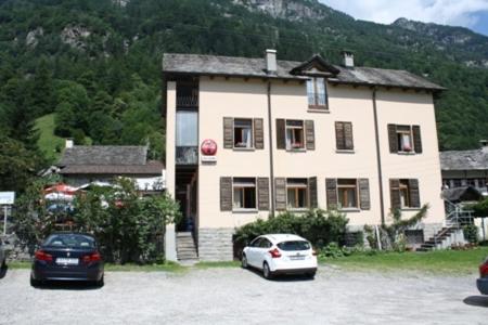 two cars parked in front of a large house at Ristorante Alpino in Sonogno