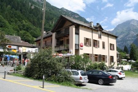 un groupe de voitures garées devant un bâtiment dans l'établissement Ristorante Alpino, à Sonogno