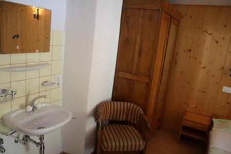 ein Bad mit einem Waschbecken und einem Stuhl neben einer Tür in der Unterkunft Ristorante Alpino in Sonogno