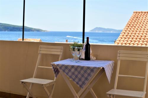 a table with two chairs and a bottle of wine at Bed and Breakfast BLUE in BLUE in Komiža