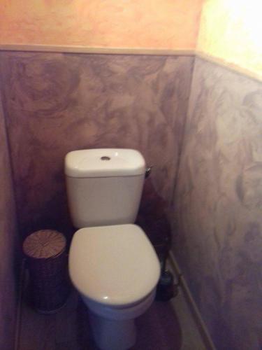 a bathroom with a white toilet in a stall at Le chant des oiseaux in Nibas